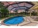 A screened-in pool and spa overlook a tranquil lake, surrounded by lush tropical landscaping at 7574 Camden Harbour Dr, Bradenton, FL 34212