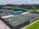 Aerial view of several tennis courts, showing people enjoying tennis with shade at 7724 Palm Aire Ln, Sarasota, FL 34243