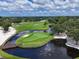 High-angle shot of a golf course featuring a pond, fountain, bridge, and manicured green spaces at 7724 Palm Aire Ln, Sarasota, FL 34243
