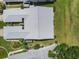 An aerial view of the property showing a well-maintained roof, lush landscaping, and surrounding greenery at 7724 Palm Aire Ln, Sarasota, FL 34243