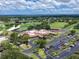 Aerial view showcasing a golf course and country club with surrounding green spaces and parking at 7724 Palm Aire Ln, Sarasota, FL 34243