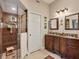 Well-lit bathroom includes a double vanity, framed mirrors, walk-in shower with seat, and ample storage at 7724 Palm Aire Ln, Sarasota, FL 34243