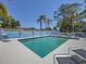 A bright and inviting community pool area featuring lounge chairs, a privacy fence, and mature palm trees at 7724 Palm Aire Ln, Sarasota, FL 34243