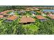 Aerial view of a single-Gathering home and surrounding neighborhood shows lush landscaping, tile roofs, and lake views at 9734 Carnoustie Pl, Bradenton, FL 34211