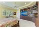 Bright bedroom featuring a custom dark wood media center, ceiling fan, and large windows at 9734 Carnoustie Pl, Bradenton, FL 34211