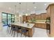 Open kitchen with an island, breakfast bar, wooden cabinets, modern appliances, and a sliding glass door at 9734 Carnoustie Pl, Bradenton, FL 34211
