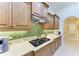 Close up view of kitchen with wood cabinetry, stainless steel range hood, green tile backsplash, and laminate countertops at 9734 Carnoustie Pl, Bradenton, FL 34211