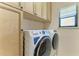 Laundry room featuring high end washer and dryer appliances with storage cabinets at 9734 Carnoustie Pl, Bradenton, FL 34211