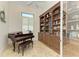 Office with a piano, shutters on the window, and a large built in wood bookshelf and cabinets at 9734 Carnoustie Pl, Bradenton, FL 34211