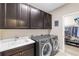 Laundry room featuring dark cabinets, a sink, and a modern washer and dryer set at 13116 Bliss Loop, Bradenton, FL 34211