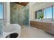 Modern bathroom features a glass enclosed shower, soaking tub, and double vanity with lots of natural light at 111 Golden Gate Pt # 802Ph, Sarasota, FL 34236