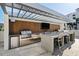 Outdoor kitchen area with stainless steel appliances, a built-in grill, and a shaded dining area at 111 Golden Gate Pt # 802Ph, Sarasota, FL 34236