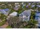 Aerial view of the home featuring mature trees, lush landscaping, a yard, and a quiet neighborhood at 113 Maple Ave, Anna Maria, FL 34216