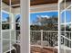 Charming balcony view through French doors of lush foliage and bright blue skies at 113 Maple Ave, Anna Maria, FL 34216