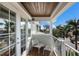 Balcony with seating overlooks the neighborhood with palm trees and blue skies at 113 Maple Ave, Anna Maria, FL 34216