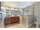 Well-lit bathroom featuring a double vanity, a glass-enclosed shower, and neutral-toned tiles at 113 Maple Ave, Anna Maria, FL 34216