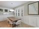 Elegant dining room with modern lighting, large windows, wainscoting, and a wooden table at 113 Maple Ave, Anna Maria, FL 34216