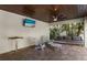 Covered patio with lounge area, television, table, chairs, and brick flooring at 113 Maple Ave, Anna Maria, FL 34216