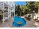 Beautiful pool with lounge chairs and spa surrounded by mature tropical trees and lush landscaping at 113 Maple Ave, Anna Maria, FL 34216