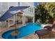 Beautiful pool with lounge chairs, swim-up table and spa surrounded by mature tropical trees and lush landscaping at 113 Maple Ave, Anna Maria, FL 34216