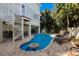 Beautiful pool with lounge chairs and spa surrounded by mature tropical trees and lush landscaping at 113 Maple Ave, Anna Maria, FL 34216