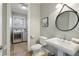 Stylish powder room featuring a pedestal sink, round mirror, and convenient access to the laundry area at 113 Maple Ave, Anna Maria, FL 34216