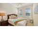 Cozy bedroom with a woven headboard, decorative pillows, and natural light from two windows at 11847 Meadowgate Pl, Lakewood Ranch, FL 34211
