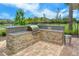 Outdoor grill area with granite countertops, stone base, and views of the landscaped surroundings at 11847 Meadowgate Pl, Lakewood Ranch, FL 34211