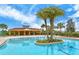 Community pool with a central island, covered seating area, and plenty of lounge chairs under swaying palm trees at 11847 Meadowgate Pl, Lakewood Ranch, FL 34211