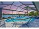 Sunset view of the screened-in pool with a hammock, waterfall feature, and scenic lake views at 11913 Blue Hill Trl, Bradenton, FL 34211