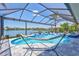Relaxing screened-in pool with a hammock, waterfall feature, and scenic lake views at 11913 Blue Hill Trl, Bradenton, FL 34211