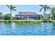Back of the home overlooking the lake, lush green grass, and a screened-in lanai with a pool at 11913 Blue Hill Trl, Bradenton, FL 34211