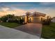 Beautiful home illuminated at dusk, showcasing its brick-paved driveway and lush landscaping at 12565 Ryegrass Loop, Parrish, FL 34219