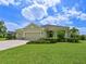 Attractive single-story home featuring a lush green lawn, a three-car garage, and colorful flowering shrubbery at 16711 Rivers Reach Blvd, Parrish, FL 34219