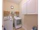 Efficient laundry room with modern washer and dryer units, overhead shelving for ample storage solutions at 16711 Rivers Reach Blvd, Parrish, FL 34219