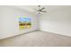 Bright bedroom with a ceiling fan and large window offering a view of the backyard at 16849 Castoro Dr, Port Charlotte, FL 33953