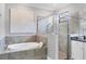 Bathroom showcasing a soaking tub, glass enclosed shower, decorative wall art and white cabinets at 18045 Polo Trail St, Bradenton, FL 34211