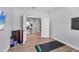 Bright, open space in the home gym featuring wood flooring, a flatscreen TV, and doorway leading into the home at 18045 Polo Trail St, Bradenton, FL 34211