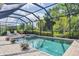 Sparkling screened-in pool with hot tub surrounded by lush landscaping, lounge chairs, and ample deck space at 18045 Polo Trail St, Bradenton, FL 34211