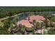 Aerial view of a luxurious home with a terracotta roof, surrounded by palm trees and a tranquil lake at 19208 Ganton Ave, Lakewood Ranch, FL 34202