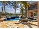 Luxury home backyard featuring a stunning pool, lush palm trees, and serene lakeside views at 19208 Ganton Ave, Lakewood Ranch, FL 34202