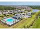 An aerial view of a community pool with seating and a pool house amidst lush green lawns at 2072 Mackerel St, Port Charlotte, FL 33953