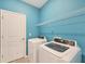 A bright laundry room with a modern washer and dryer, overhead shelving, and a door to another area at 2072 Mackerel St, Port Charlotte, FL 33953