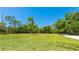 Expansive green backyard, surrounded by tall trees, provides privacy and space for outdoor activities at 222 High Point Dr, Venice, FL 34292