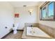 Bright bathroom featuring a modern toilet, built-in tub, and a large window for natural light at 222 High Point Dr, Venice, FL 34292