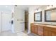Bathroom with double sinks, wood cabinets, and a walk-in tiled shower at 222 High Point Dr, Venice, FL 34292