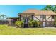 Back exterior elevation featuring a screened-in porch, lush landscaping, and a brick foundation at 222 High Point Dr, Venice, FL 34292