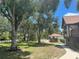 A charming home exterior featuring mature trees and lush green lawn at 222 High Point Dr, Venice, FL 34292