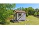 Cozy backyard shed with a brown roof and white siding sits on the property's manicured lawn at 222 High Point Dr, Venice, FL 34292