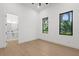 A minimalist bedroom with wood floors and two large windows with lush green views at 2632 Hawthorne St, Sarasota, FL 34239